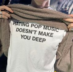 a woman holding up a t - shirt that says hating pop music doesn't make you deep