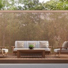 an outdoor seating area with wooden slatted walls and white cushions on the patio