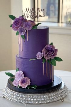 a three tiered purple cake with flowers on top