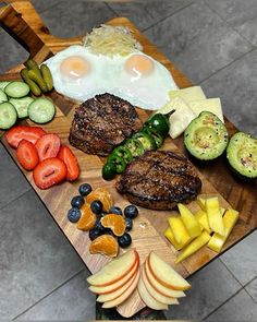 a wooden cutting board topped with meat and veggies next to an egg on top of a pile of cheese