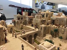 a model of a castle made out of sand with cars parked in the back ground