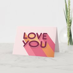 a card with the words love you on it next to a vase filled with flowers