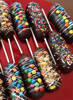 chocolate covered donuts with sprinkles and toppings on a red plate