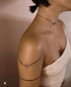 a woman with a small tattoo on her left shoulder and arm, looking to the side