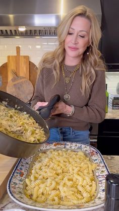 a woman is cooking pasta in the kitchen and she is holding a frying pan