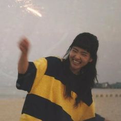 a woman in a yellow and black striped sweater is holding a sparkler on the beach