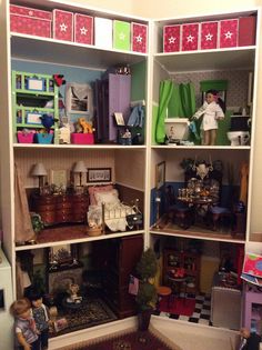 two children playing in a dollhouse with toys on the floor and shelves above them