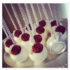 there are some white eggs with red roses on them and silver chains hanging from the top