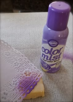 a purple bottle sitting on top of a table next to a doily and lace