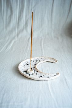 a ceramic moon with two wooden sticks sticking out of it's side on a white background