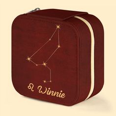 a red lunch box with the zodiac sign on it's side and name written in gold