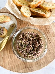 there is a bowl of food on the table next to some breads and butter