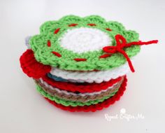 crocheted coasters stacked on top of each other with red and green ribbons