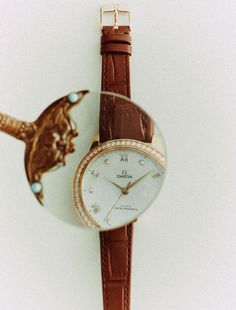 a watch with an image of a bird on the dial and brown leather strap around it