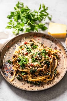 a plate full of spaghetti with sauce and parmesan cheese on the side next to some parsley