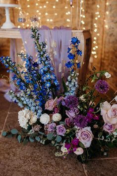 a bouquet of flowers sitting on top of a floor next to a chair with lights in the background