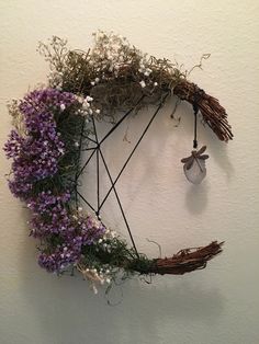 a wreath made out of twigs and flowers hanging on the wall next to a light bulb