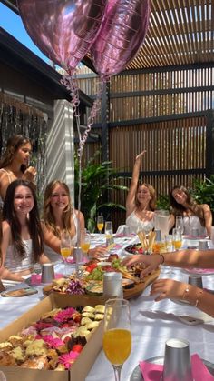 a group of women sitting around a table with food and drinks