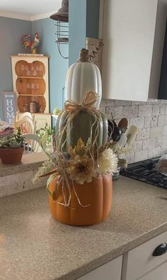 a kitchen counter with a pumpkin shaped container filled with flowers and other things on it