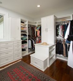 an organized closet with white cabinets, drawers and rugs on the hardwood flooring