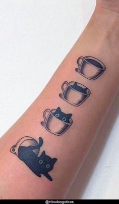 a tattoo with cats and cups on the arm