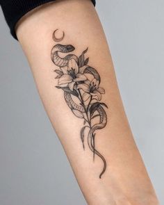 a woman's arm with a snake and flowers tattoo on it