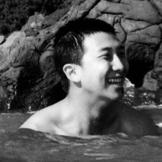 black and white photograph of a man in the water with his eyes closed, smiling