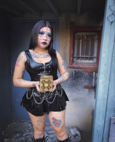 a woman with tattoos and piercings on her face standing in front of a door