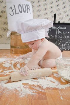 a baby in a chef's hat rolling dough on the floor