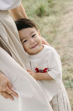 a little boy is smiling while holding his mother's arm