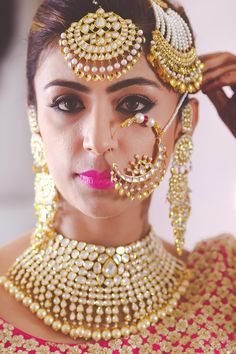 a woman in a bridal outfit with gold jewelry on her head and nose ring