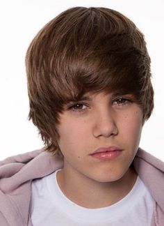 a young boy wearing a pink jacket and white t - shirt is looking at the camera