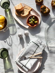 a table topped with plates filled with food next to glasses and utensils on top of a striped cloth