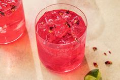 two glasses filled with ice and garnish next to a slice of lime