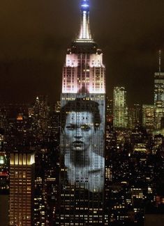 an image of a man's face is projected on the side of a building