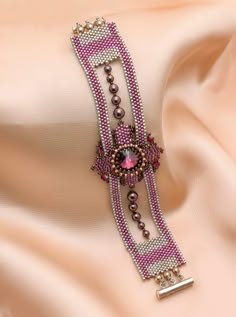 the bracelet is adorned with beads and other jewelry items on top of a pink cloth