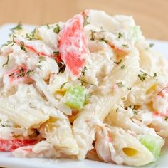 a white plate topped with pasta salad on top of a wooden table