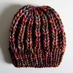 a multicolored knitted beanie sitting on top of a white surface