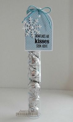 a snowflakes are kisses from above candy in a clear tube with blue ribbon