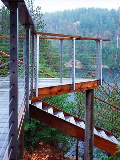 a wooden bridge over a body of water surrounded by trees and bushes in the background