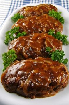 three pieces of meat covered in gravy on a white plate