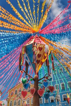 colorful kites are being flown in the sky above a building with many hearts on it