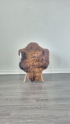 a chair made out of fur sitting on top of a hard wood floor next to a wall