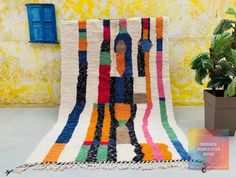 a multicolored area rug next to a potted plant