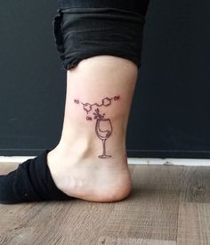 a woman's foot with a wine glass tattoo on it