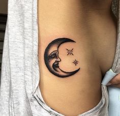 a woman's stomach with a crescent moon and stars tattoo on her left side