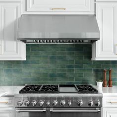 a stove top oven sitting inside of a kitchen next to white cabinets and counter tops