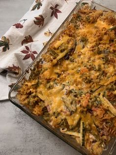 a casserole dish filled with green beans, cheese and other toppings on a table