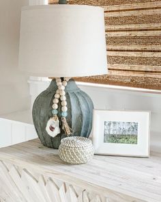 a lamp sitting on top of a wooden dresser next to a framed photo and an art piece