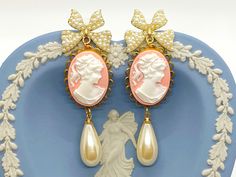 "These beautiful vintage inspired earrings were created with the sweetest pearl bow post earrings adorned with brass scalloped settings with pink and white Cameo cabochons and vintage cream teardrop pearls. These cameo statement earrings hang beautifully from the ear and measure 2 3/4 inches in length and 7/8 inches in width. These earrings make the \"perfect gift\" for your mom, sister, daughter, friend, girlfriend, wife or bridesmaids....She will truly love these and treasure them for many yea Pink Feminine Pearl Earrings, Victorian Pearl Earrings For Pierced Ears, Elegant Cameo Dangle Earrings, Pink Pearl Bridal Earrings As Gift, Pink Pearl Bridal Earrings For Gift, Pink Dangle Pearl Earrings For Formal Occasions, Pink Pearl Earrings For Pierced Ears, Elegant Handmade Pink Clip-on Earrings, Pink Victorian Earrings For Gift